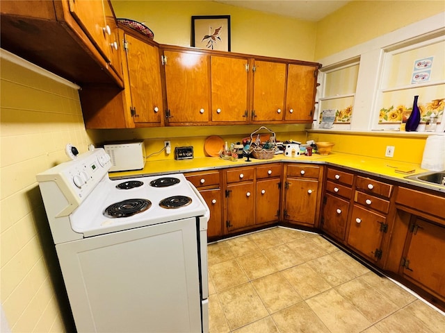 1019 10th Ave W, Bradenton, FL 34205 - kitchen featuring white electric range, brown cabinets, light tile patterned floors, and light countertops