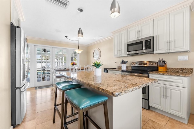 1723 Laramie St, Sarasota, FL 34231 - kitchen with stainless steel appliances, light stone counters, crown molding, light tile patterned floors, and a center island