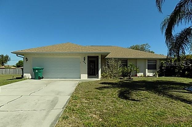 408 Fletcher St, Port Charlotte, FL 33954 - ranch-style house with a front yard, driveway, an attached garage, and stucco siding