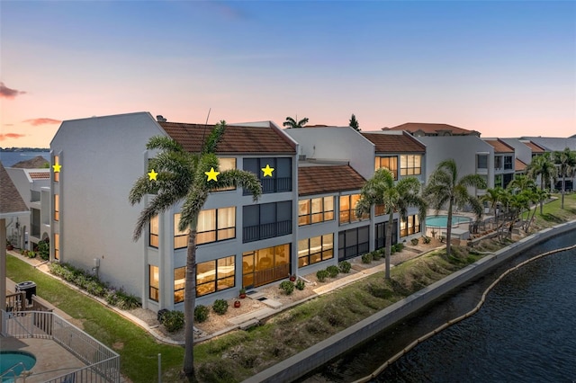 4210 SE 20th Pl Unit A8, Cape Coral, FL 33904 - back of property at dusk with a tiled roof, stucco siding, a water view, and a residential view