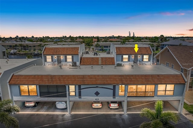 4210 SE 20th Pl Unit A8, Cape Coral, FL 33904 - back of property at dusk featuring a tile roof, covered parking, a residential view, and stucco siding