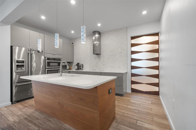 5240 Bentgrass Way, Bradenton, FL 34211 - kitchen featuring appliances with stainless steel finishes, modern cabinets, wall chimney range hood, light wood-style floors, and recessed lighting