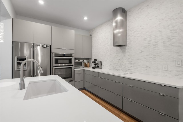 5240 Bentgrass Way, Bradenton, FL 34211 - kitchen featuring gray cabinets, stainless steel appliances, a sink, light wood finished floors, and tasteful backsplash