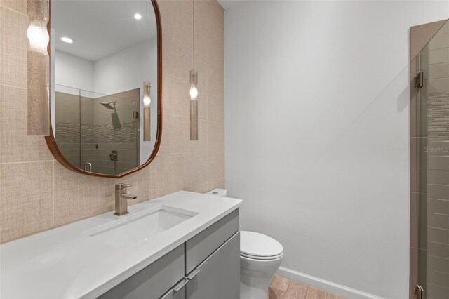 5240 Bentgrass Way, Bradenton, FL 34211 - bathroom featuring vanity, a tile shower, toilet, wood finished floors, and tile walls
