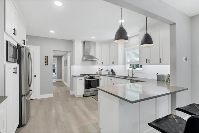 1919 Laurel St, Sarasota, FL 34236 - kitchen with wall chimney range hood, appliances with stainless steel finishes, backsplash, light wood-type flooring, and a peninsula