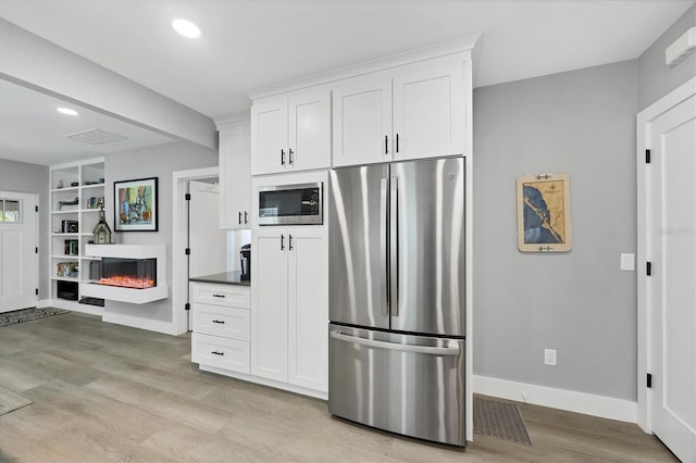 1919 Laurel St, Sarasota, FL 34236 - kitchen with appliances with stainless steel finishes, a glass covered fireplace, light wood-style flooring, white cabinets, and recessed lighting