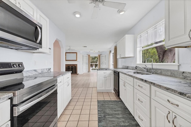 2002 8th St W, Palmetto, FL 34221 - kitchen featuring stainless steel appliances, a ceiling fan, plenty of natural light, and a brick fireplace