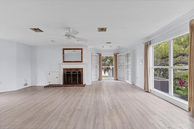 2002 8th St W, Palmetto, FL 34221 - unfurnished living room featuring light wood-style flooring, ceiling fan, a brick fireplace, and baseboards