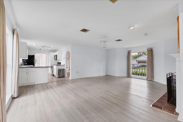 2002 8th St W, Palmetto, FL 34221 - unfurnished living room featuring ceiling fan, arched walkways, light wood-type flooring, and a sink