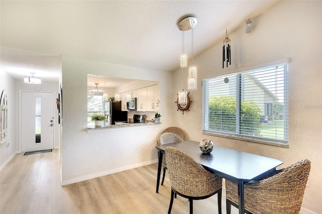 6024 28th St W, Bradenton, FL 34207 - dining room featuring light wood-style floors, a textured ceiling, lofted ceiling, and a textured wall