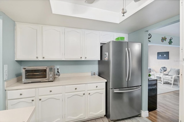2740 Orchid Oaks Dr Unit 304, Sarasota, FL 34239 - kitchen featuring freestanding refrigerator, white cabinetry, light countertops, and light wood-type flooring
