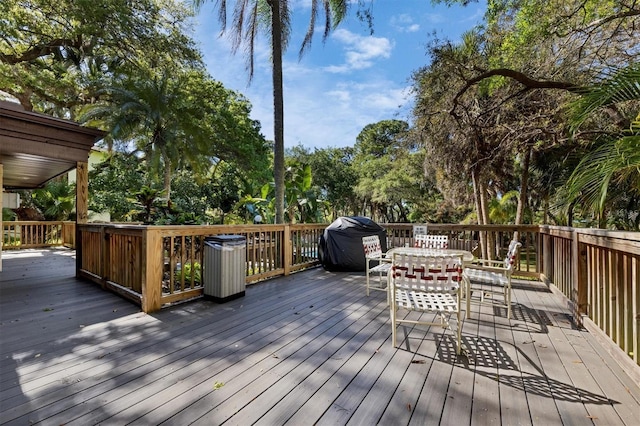 2740 Orchid Oaks Dr Unit 304, Sarasota, FL 34239 - wooden terrace featuring a grill, outdoor dining space, and view of wooded area