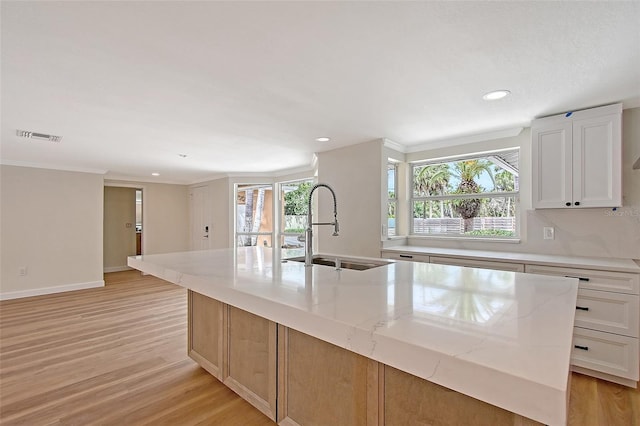 1203 Lyric Ln, Sarasota, FL 34242 - kitchen featuring an island with sink, light wood finished floors, light stone countertops, recessed lighting, and white cabinets