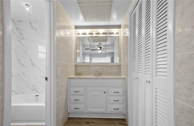 222 Caddy Rd, Rotonda West, FL 33947 - bathroom featuring a closet, tile walls, vanity, wood finished floors, and a ceiling fan