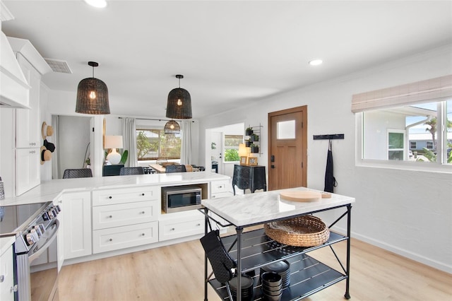 404 Bayshore Rd, Nokomis, FL 34275 - kitchen featuring appliances with stainless steel finishes, white cabinetry, light wood-style flooring, light countertops, and pendant lighting
