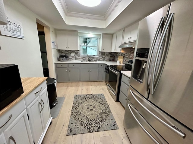 3272 Lake Bayshore Dr Unit 515, Bradenton, FL 34205 - kitchen featuring appliances with stainless steel finishes, a sink, light wood finished floors, a raised ceiling, and crown molding