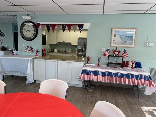 3272 Lake Bayshore Dr Unit 515, Bradenton, FL 34205 - kitchen featuring dark wood-type flooring, a paneled ceiling, black fridge with ice dispenser, white cabinets, and stone countertops