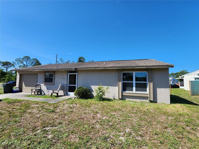 6405 Myrtlewood Rd, North Port, FL 34287 - rear view of property with stucco siding, an attached garage, and a yard