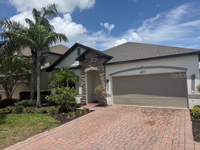 4077 River Bank Way, Punta Gorda, FL 33980 - view of front facade with decorative driveway, stucco siding, stone siding, and an attached garage