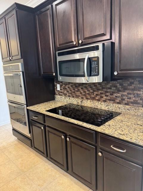 4077 River Bank Way, Punta Gorda, FL 33980 - kitchen with appliances with stainless steel finishes, decorative backsplash, light stone counters, and dark brown cabinetry