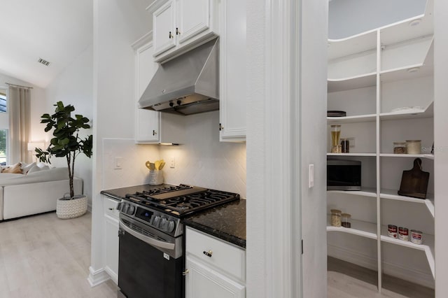 12015 Forest Park Cir, Bradenton, FL 34211 - kitchen with stainless steel gas stove, light wood-style flooring, backsplash, dark stone countertops, and lofted ceiling