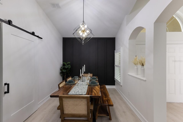 12015 Forest Park Cir, Bradenton, FL 34211 - dining area featuring light wood-style flooring, a decorative wall, arched walkways, baseboards, and a barn door