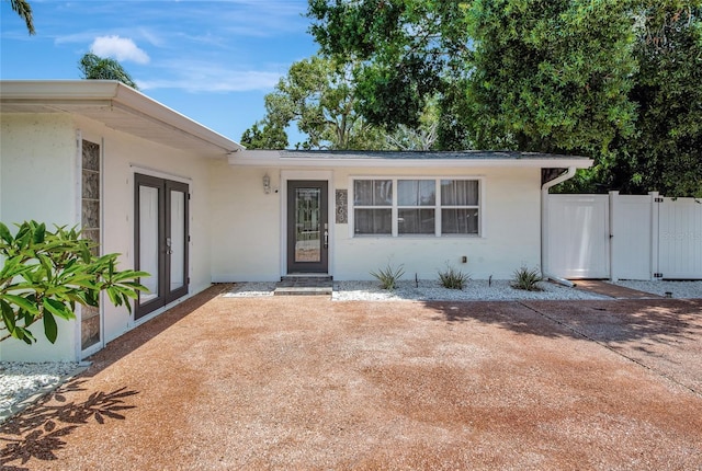 2363 Milford Cir, Sarasota, FL 34239 - view of exterior entry with stucco siding, french doors, and a gate