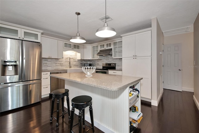 2363 Milford Cir, Sarasota, FL 34239 - kitchen with appliances with stainless steel finishes, backsplash, white cabinets, and a center island