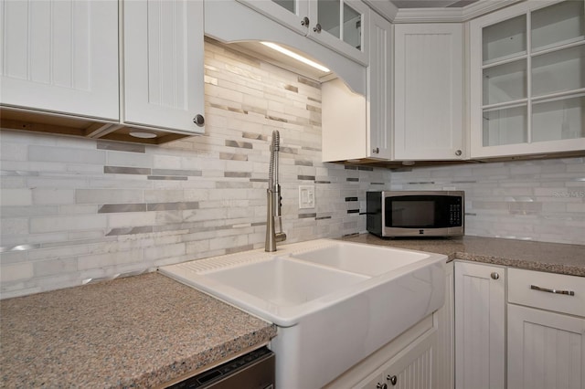 2363 Milford Cir, Sarasota, FL 34239 - kitchen featuring stainless steel microwave, a sink, backsplash, white cabinets, and glass insert cabinets