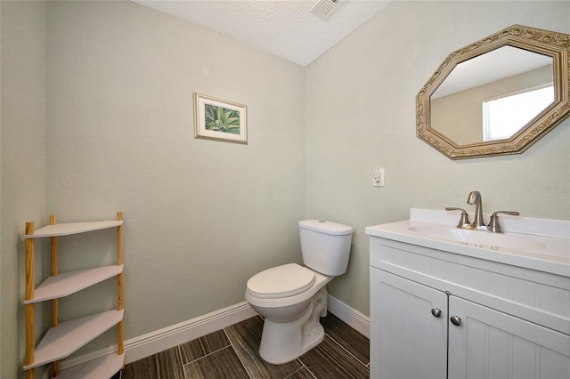 2363 Milford Cir, Sarasota, FL 34239 - half bathroom with vanity, toilet, baseboards, a textured ceiling, and wood tiled floors