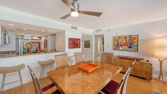 988 Blvd Of The Arts Unit 1016, Sarasota, FL 34236 - dining space with light wood-type flooring, a textured ceiling, a ceiling fan, and crown molding