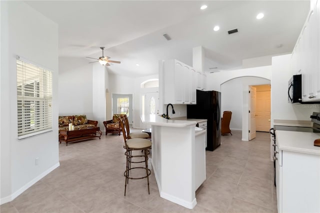 2199 Palm Ct, North Port, FL 34287 - kitchen with arched walkways, a kitchen breakfast bar, ceiling fan, white cabinetry, and a peninsula