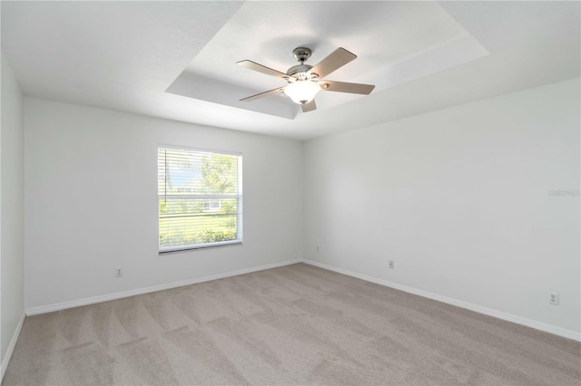 2199 Palm Ct, North Port, FL 34287 - empty room with light colored carpet, a ceiling fan, a tray ceiling, and baseboards