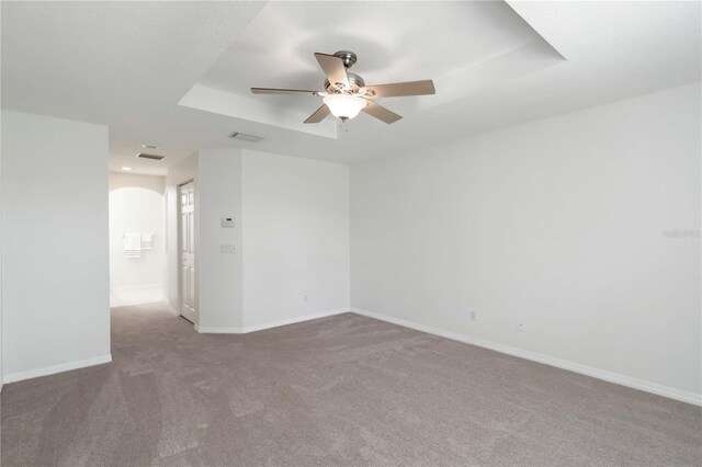 2199 Palm Ct, North Port, FL 34287 - carpeted empty room featuring a tray ceiling, a ceiling fan, baseboards, and arched walkways
