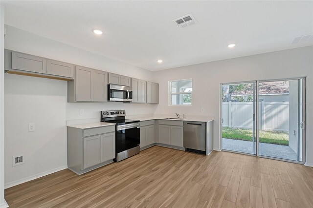 1643 35th St, Sarasota, FL 34234 - kitchen featuring appliances with stainless steel finishes, gray cabinetry, light wood-style flooring, a sink, and recessed lighting