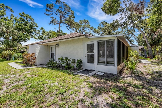 5356 Royal Palm Ave Unit 5356, Sarasota, FL 34234 - back of house featuring stucco siding, a sunroom, and a lawn