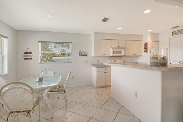 4484 Tortoise Rd, Venice, FL 34293 - kitchen with white microwave, light countertops, white cabinets, light tile patterned flooring, and recessed lighting