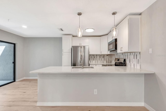 5192 Cedar Hammock Ln, Sarasota, FL 34232 - kitchen featuring appliances with stainless steel finishes, light countertops, a peninsula, white cabinets, and recessed lighting