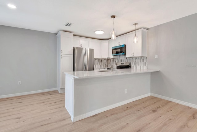 5192 Cedar Hammock Ln, Sarasota, FL 34232 - kitchen featuring appliances with stainless steel finishes, a sink, light wood-type flooring, light countertops, and a peninsula