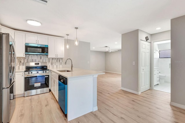 5192 Cedar Hammock Ln, Sarasota, FL 34232 - kitchen featuring appliances with stainless steel finishes, a sink, a peninsula, white cabinets, and light wood-type flooring