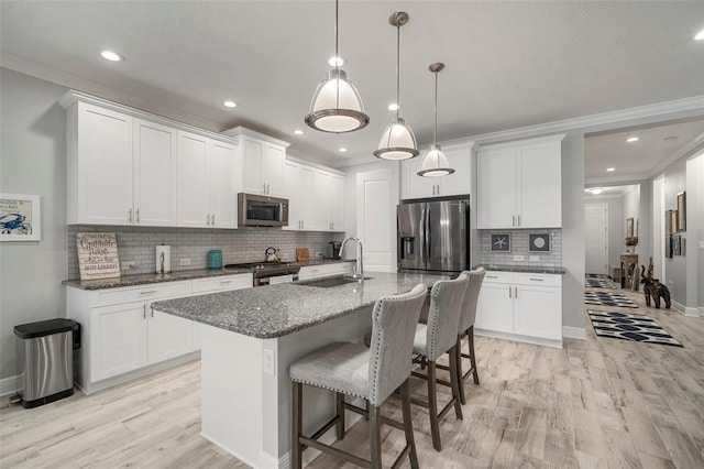 10423 Morning Marsh Ln, Parrish, FL 34219 - kitchen featuring stainless steel appliances, light wood-style floors, a breakfast bar, a sink, and decorative backsplash