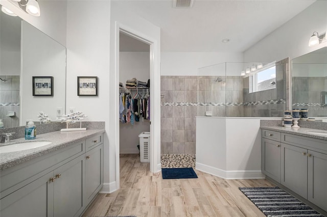 10423 Morning Marsh Ln, Parrish, FL 34219 - bathroom featuring two vanities, walk in shower, and wood finished floors
