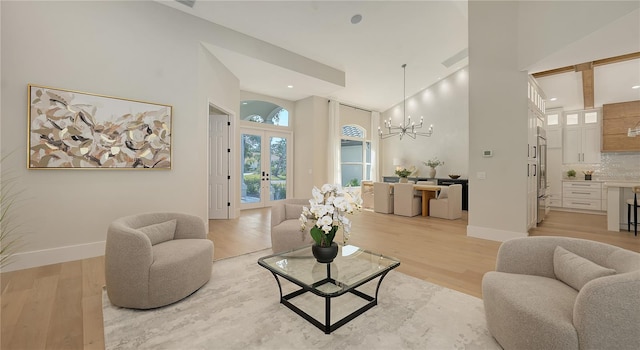 6641 Saint James Xing, University Park, FL 34201 - living room featuring light wood-style flooring, a chandelier, french doors, a towering ceiling, and baseboards
