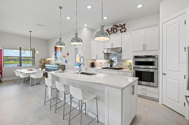 5740 Eagle Creek Rd, Sarasota, FL 34238 - kitchen with a sink, under cabinet range hood, stainless steel double oven, gas cooktop, and backsplash
