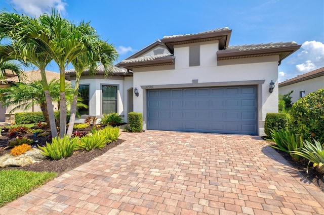 5740 Eagle Creek Rd, Sarasota, FL 34238 - mediterranean / spanish house featuring decorative driveway, stucco siding, an attached garage, and a tiled roof