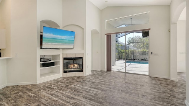 6213 Willet Ct, Lakewood Ranch, FL 34202 - unfurnished living room with wood finished floors, high vaulted ceiling, built in shelves, baseboards, and a tile fireplace