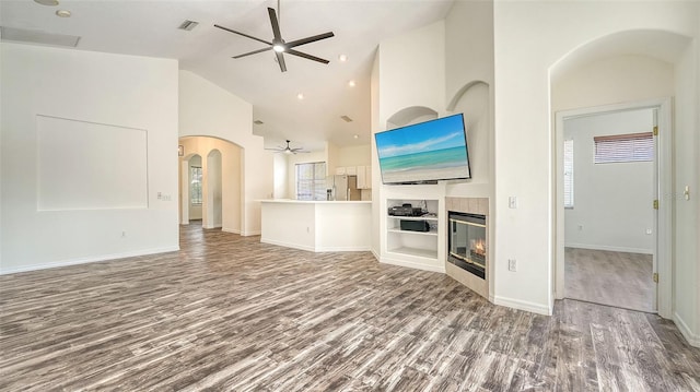 6213 Willet Ct, Lakewood Ranch, FL 34202 - unfurnished living room with ceiling fan, wood finished floors, a tile fireplace, high vaulted ceiling, and arched walkways
