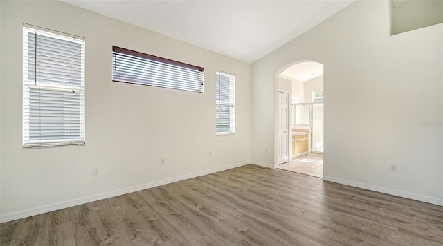 6213 Willet Ct, Lakewood Ranch, FL 34202 - empty room featuring arched walkways, wood finished floors, lofted ceiling, and baseboards