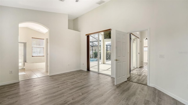 6213 Willet Ct, Lakewood Ranch, FL 34202 - unfurnished room with arched walkways, plenty of natural light, wood finished floors, baseboards, and a high ceiling