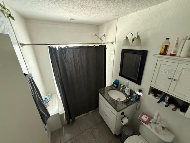 2094 Penn Dr, Deland, FL 32724 - full bathroom featuring a textured ceiling, toilet, vanity, shower / tub combo, and tile patterned flooring